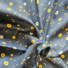 Navy twill cotton fabric with a floral print featuring golden sunflowers, white daisies, orange speckled dots and green leafy sprigs, shown draped and gathered.