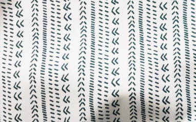 Twill cotton fabric in white with a navy geometric print of arrows, dashes, and chevron stripes.