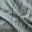 Twill cotton fabric in green with a white geometric print of arrows, dashes, and chevron stripes.