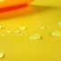 Close-up of Eco-laminated plain yellow with drops of water on surface