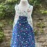 Emily's Pinafore Pretty Daisy Navy & Forest Friends White. Bottom half shows multi-coloured daisies on navy, top part forest animals on white.