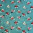 Garden Rose cotton fabric in pastel blue, featuring a pattern of red, pink, and cream roses with white and navy florals, green foliage, and coral berry sprigs on a pastel blue background