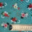 Garden Rose cotton fabric in pastel blue, featuring a pattern of red, pink, and cream roses with white and navy florals, green foliage, and coral berry sprigs on a pastel blue background
