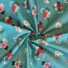 Garden Rose cotton fabric in pastel blue, featuring a pattern of red, pink, and cream roses with white and navy florals, green foliage, and coral berry sprigs on a pastel blue background