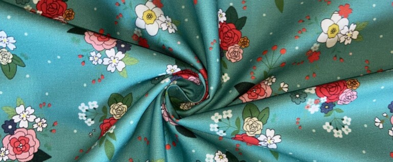 Garden Rose cotton fabric in pastel blue, featuring a pattern of red, pink, and cream roses with white and navy florals, green foliage, and coral berry sprigs on a pastel blue background