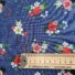 Garden Rose cotton fabric in medium sapphire, featuring a pattern of red, pink, and cream roses with white and navy florals, green foliage, and coral berry sprigs on a deep blue background